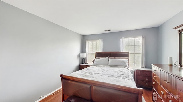 bedroom featuring baseboards, dark wood-style floors, visible vents, and multiple windows