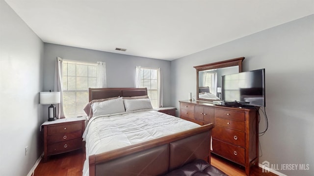 bedroom with baseboards, dark wood-style floors, and visible vents