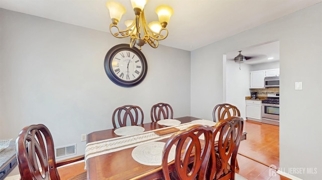dining room featuring a notable chandelier, visible vents, and light wood-style floors