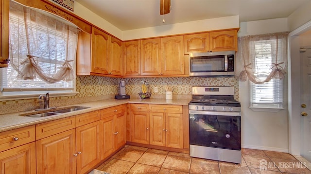 kitchen with sink, light tile patterned floors, ceiling fan, stainless steel appliances, and decorative backsplash