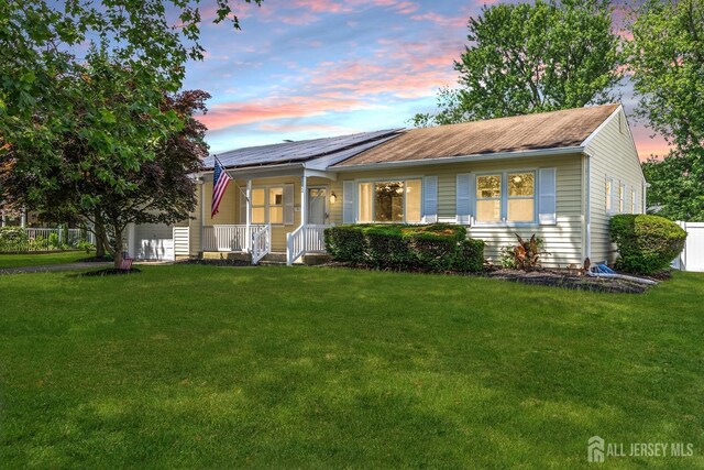 view of front of property with solar panels, a lawn, and a porch