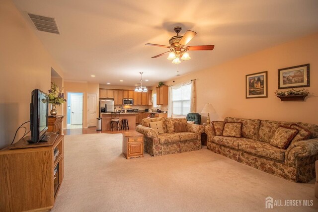 living room with light carpet, a ceiling fan, a chandelier, and recessed lighting