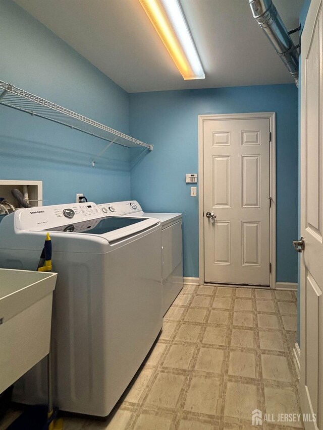 laundry room with washing machine and clothes dryer, light floors, and baseboards