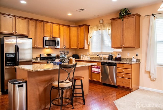 kitchen with appliances with stainless steel finishes, a kitchen island, plenty of natural light, a kitchen bar, and recessed lighting
