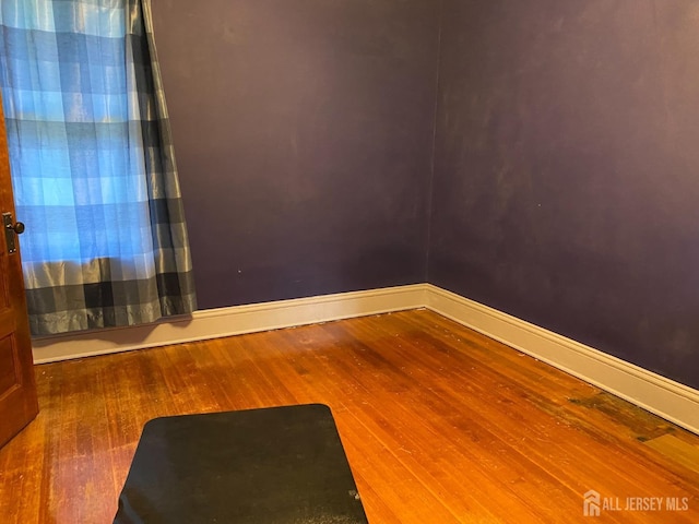 unfurnished room featuring baseboards and wood finished floors