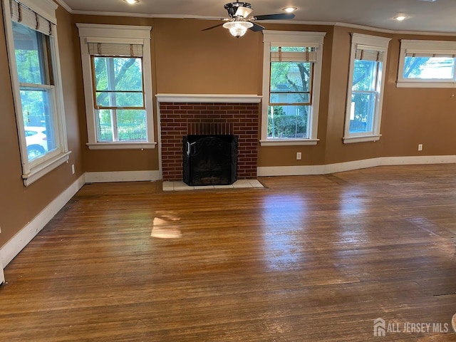 unfurnished living room featuring wood finished floors, ceiling fan, a fireplace, and crown molding