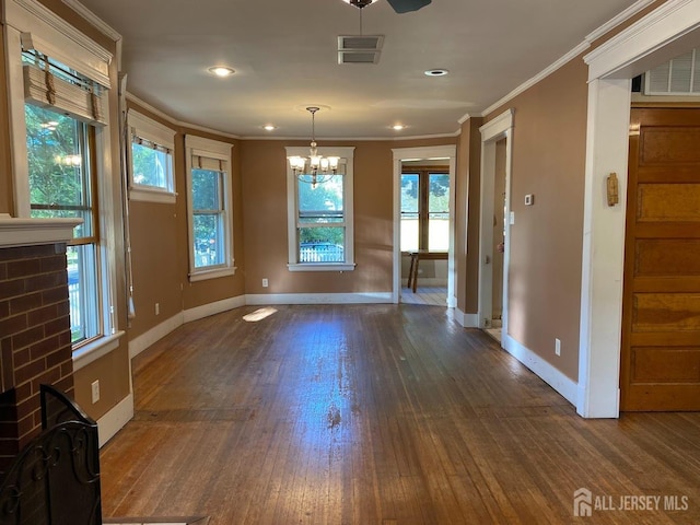 unfurnished dining area with visible vents, baseboards, dark wood finished floors, an inviting chandelier, and crown molding