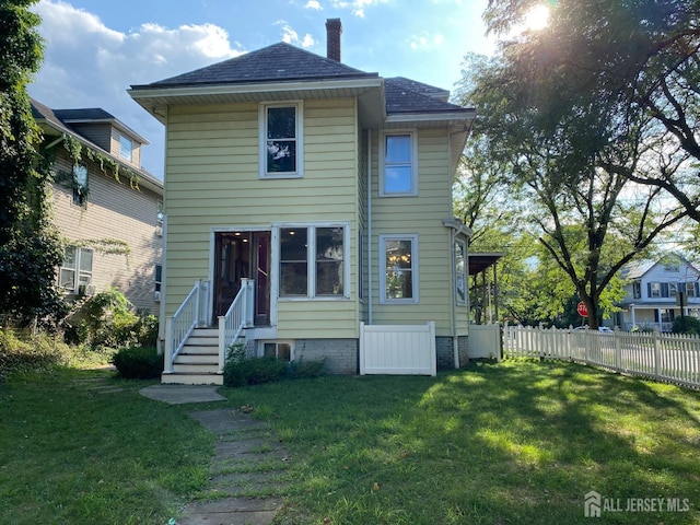 back of property with a yard, fence, roof with shingles, and a chimney