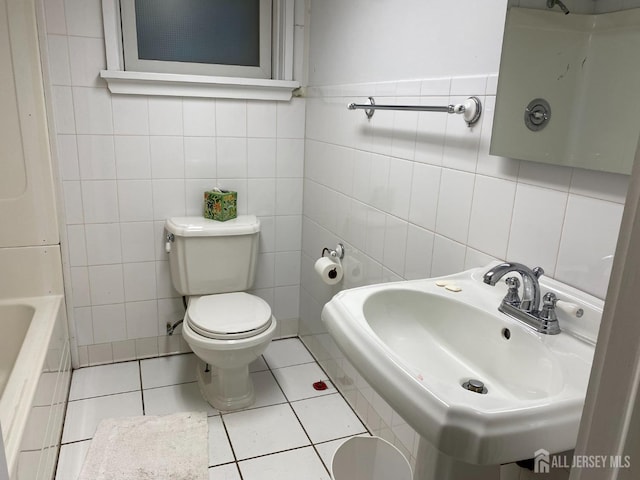 bathroom with tile patterned flooring, tile walls, toilet, and a sink