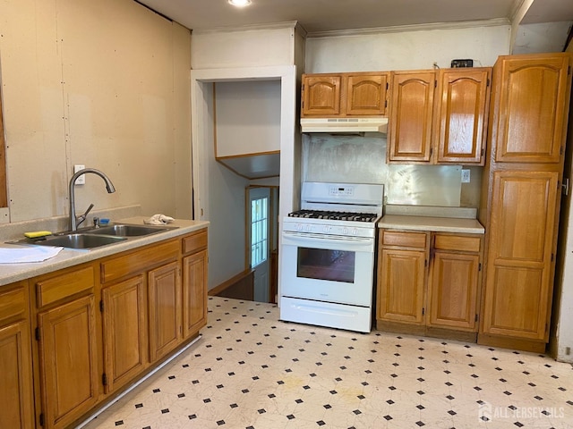 kitchen featuring a sink, white range with gas stovetop, under cabinet range hood, and light countertops