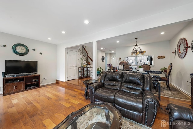 living area with recessed lighting, wood finished floors, baseboards, and stairway
