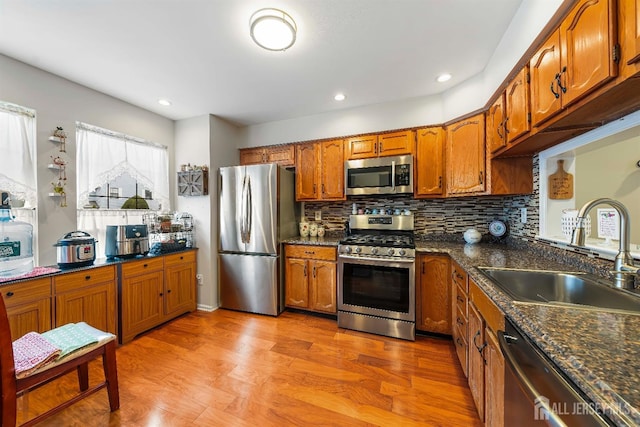 kitchen featuring brown cabinets, decorative backsplash, stainless steel appliances, and a sink