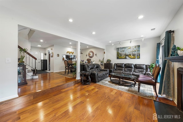 living area with wood finished floors, stairs, visible vents, and recessed lighting