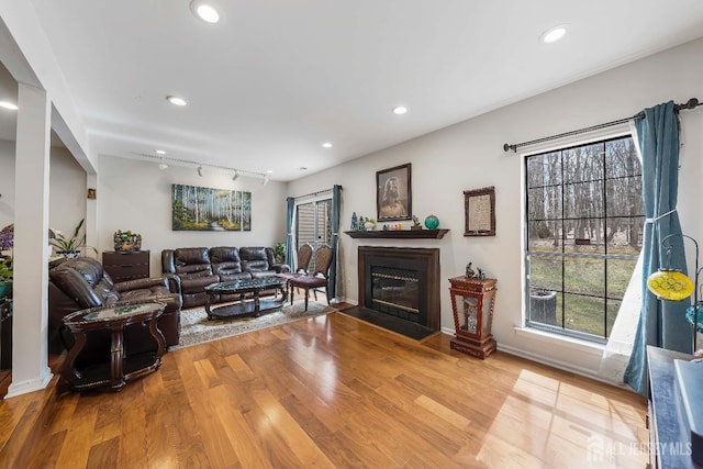 living room with a fireplace with flush hearth, baseboards, wood finished floors, and recessed lighting