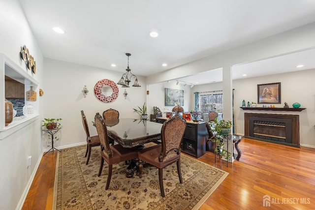 dining area featuring recessed lighting, a glass covered fireplace, wood finished floors, and baseboards