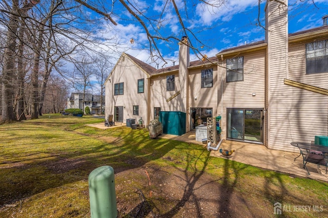 back of property featuring a chimney, a yard, and a patio