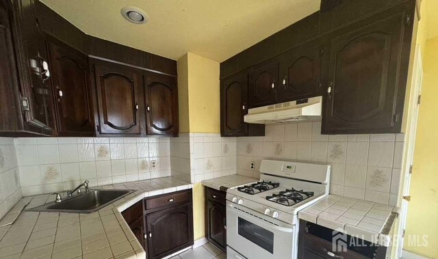 212 Middlesex Ave, Iselin, NJ 08830 - kitchen featuring gas range gas stove, tile countertops, under cabinet range hood, and dark brown cabinetry