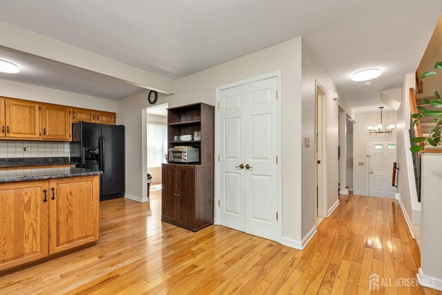 183 Driscoll Ct, Franklin Twsp, NJ 08873 - kitchen with black fridge with ice dispenser, light wood finished floors, decorative backsplash, brown cabinetry, and a chandelier