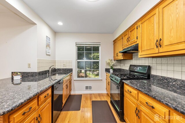 183 Driscoll Ct, Franklin Twsp, NJ 08873 - kitchen with black range with gas cooktop, stainless steel dishwasher, under cabinet range hood, light wood-style flooring, and dark stone countertops