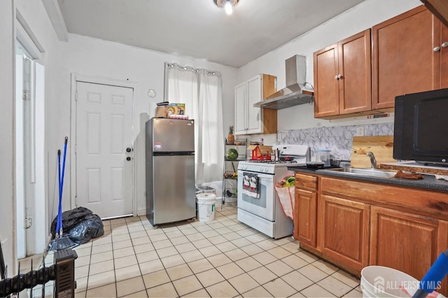 264 Washington St, Perth Amboy, NJ 08861 - kitchen with freestanding refrigerator, white gas range, wall chimney exhaust hood, a sink, and light tile patterned floors