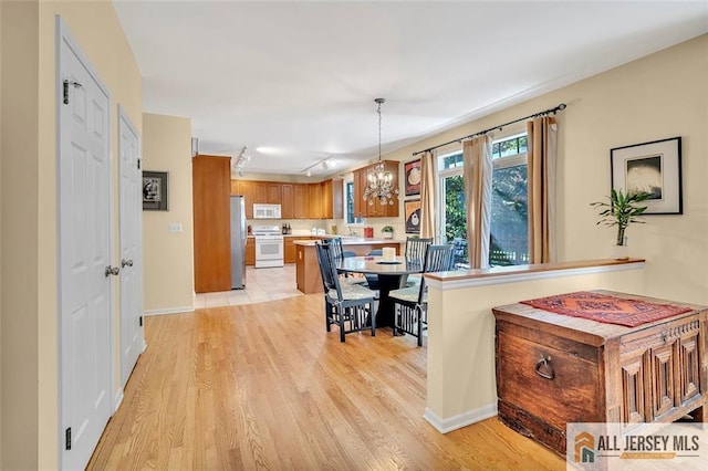 2 Danser Dr, Cranbury, NJ 08512 - kitchen with white appliances, light countertops, brown cabinetry, a chandelier, and light wood-type flooring