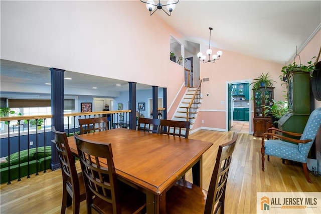 7 Hollywood St, South River, NJ 08882 - dining space featuring ornate columns, a chandelier, light wood-type flooring, high vaulted ceiling, and stairway