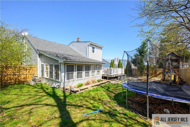 7 Hollywood St, South River, NJ 08882 - back of house featuring a trampoline, a sunroom, a fenced backyard, a chimney, and a shingled roof