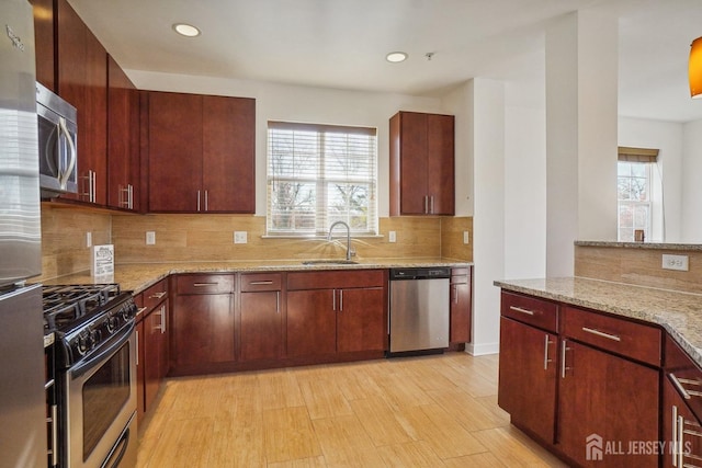 kitchen featuring sink, backsplash, light stone counters, and stainless steel appliances