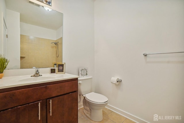 bathroom with tile patterned flooring, a tile shower, vanity, and toilet