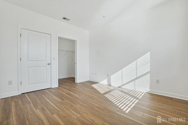 unfurnished bedroom with hardwood / wood-style flooring, a spacious closet, and a closet