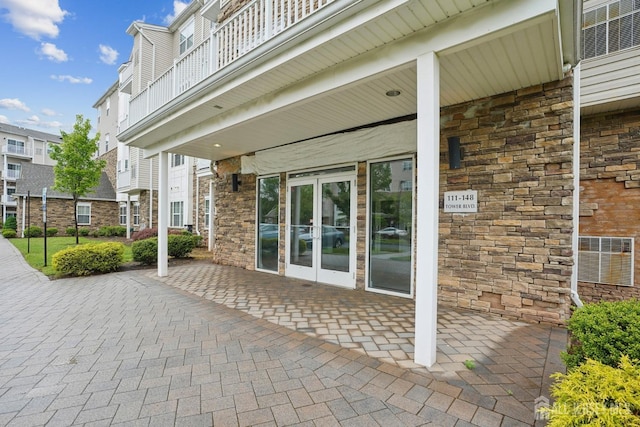 view of patio featuring french doors, a balcony, and cooling unit