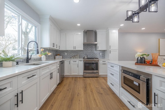 7 Winslow Ave, East Brunswick, NJ 08816 - kitchen with stainless steel appliances, wall chimney exhaust hood, light wood-type flooring, backsplash, and white cabinets