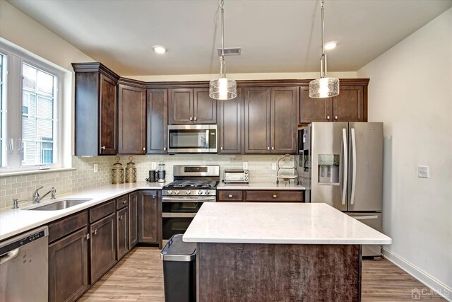2206 Stelmaszek Rd, Sayreville, NJ 08859 - kitchen with stainless steel appliances, dark brown cabinets, light wood-style floors, a center island, and tasteful backsplash