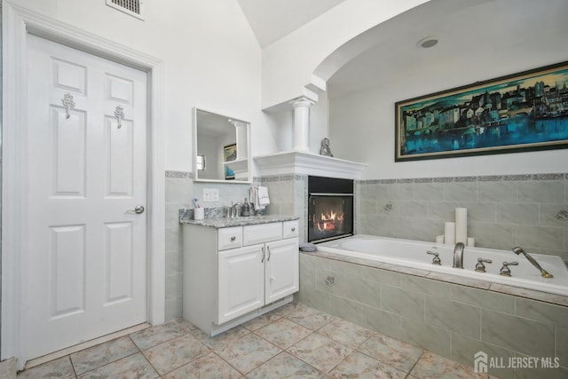 51 Greenbrook Rd, Middlesex, NJ 08846 - bathroom featuring vanity, a garden tub, a tiled fireplace, ornate columns, and vaulted ceiling