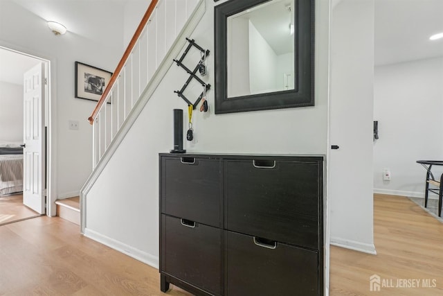 hall featuring baseboards, light wood-style flooring, and stairway