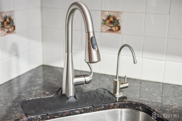 room details featuring white cabinets, modern cabinets, dark stone counters, and a sink