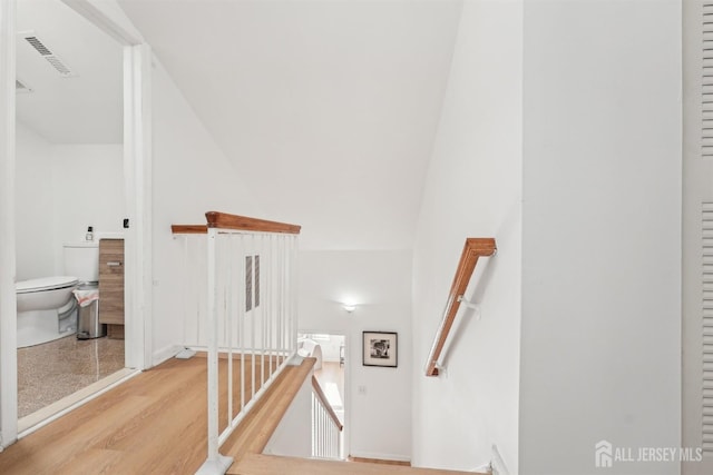 staircase with baseboards, wood finished floors, and visible vents