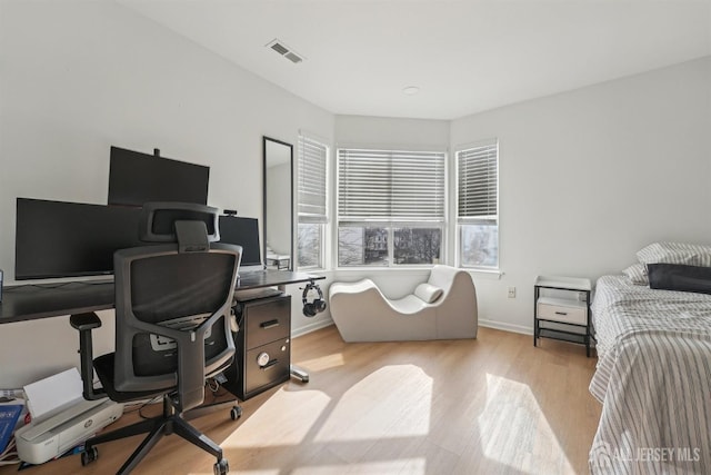 bedroom with baseboards, visible vents, and wood finished floors