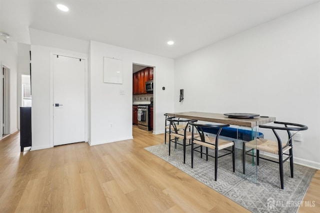 dining space featuring light wood finished floors, baseboards, and recessed lighting