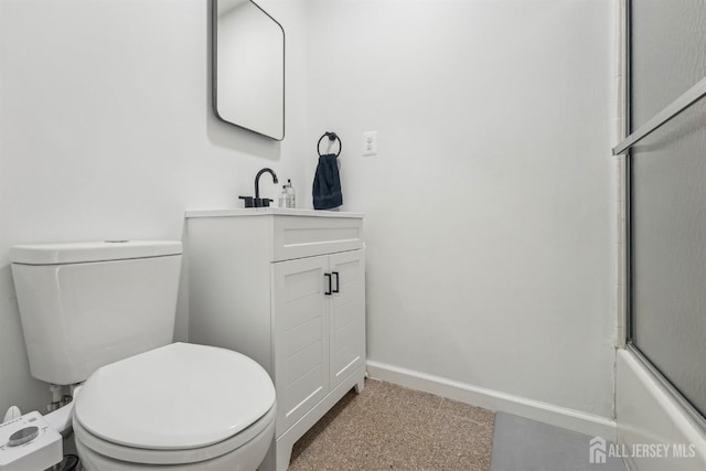 bathroom featuring combined bath / shower with glass door, baseboards, vanity, and toilet