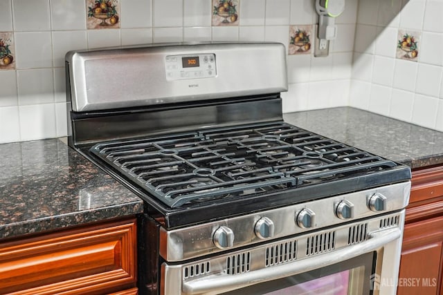 interior details with dark stone countertops, stainless steel gas range oven, and tasteful backsplash