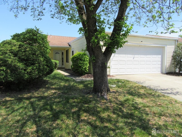 view of front of house with concrete driveway, a front lawn, and an attached garage