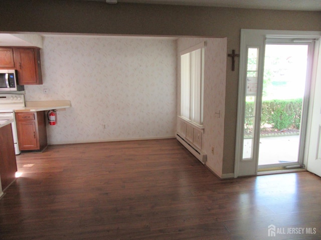 unfurnished dining area featuring baseboard heating, dark wood-style flooring, wallpapered walls, and baseboards