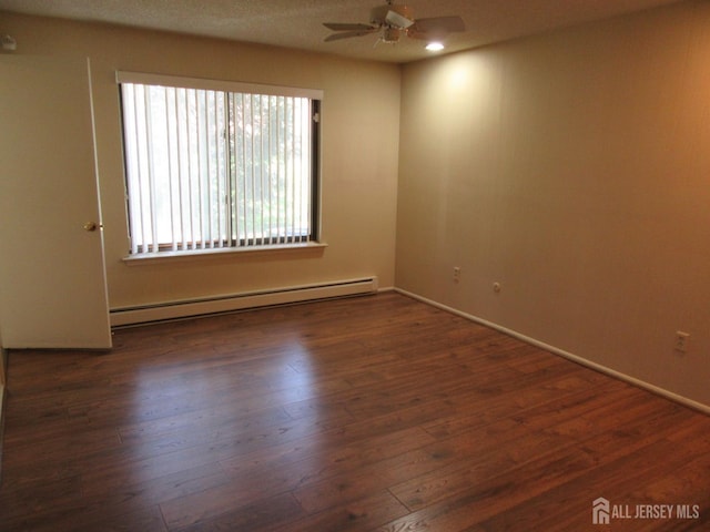 spare room featuring a baseboard heating unit, ceiling fan, wood finished floors, and baseboards