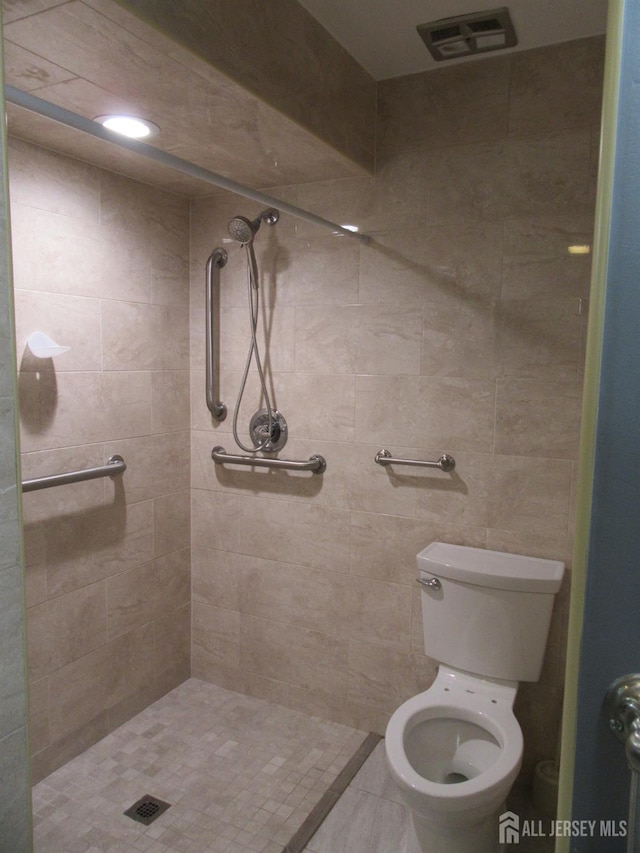 bathroom featuring tiled shower and toilet