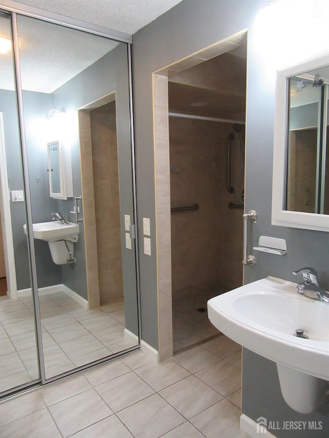 bathroom featuring tile patterned floors, walk in shower, a sink, and a textured ceiling