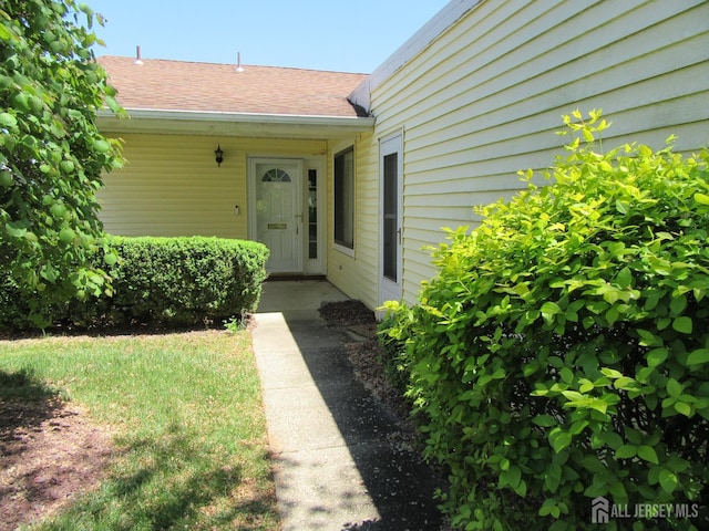 entrance to property featuring roof with shingles
