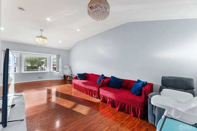 living room with hardwood / wood-style flooring, a notable chandelier, and lofted ceiling