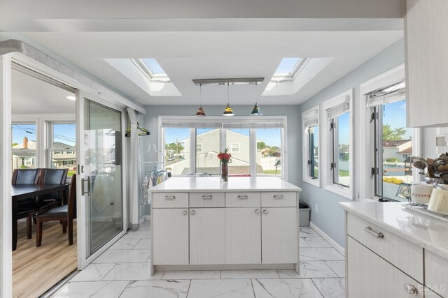 kitchen with a skylight, white cabinetry, and light wood-type flooring