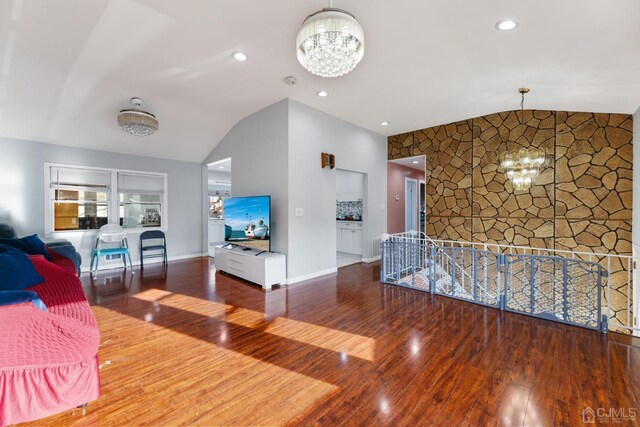 living room featuring a chandelier, vaulted ceiling, and wood-type flooring